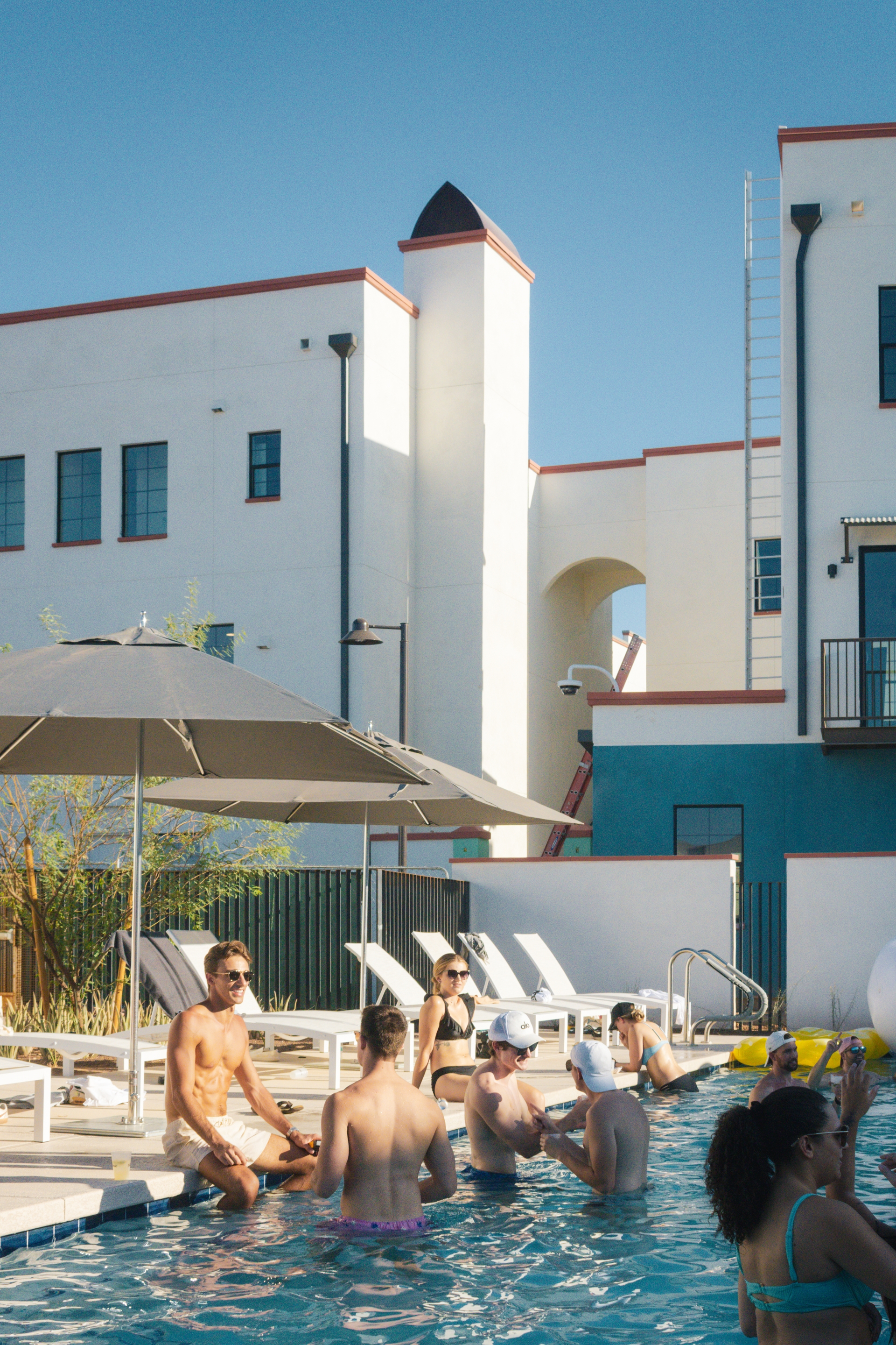 Photo of two people sitting on edge of pool with buildings in the background